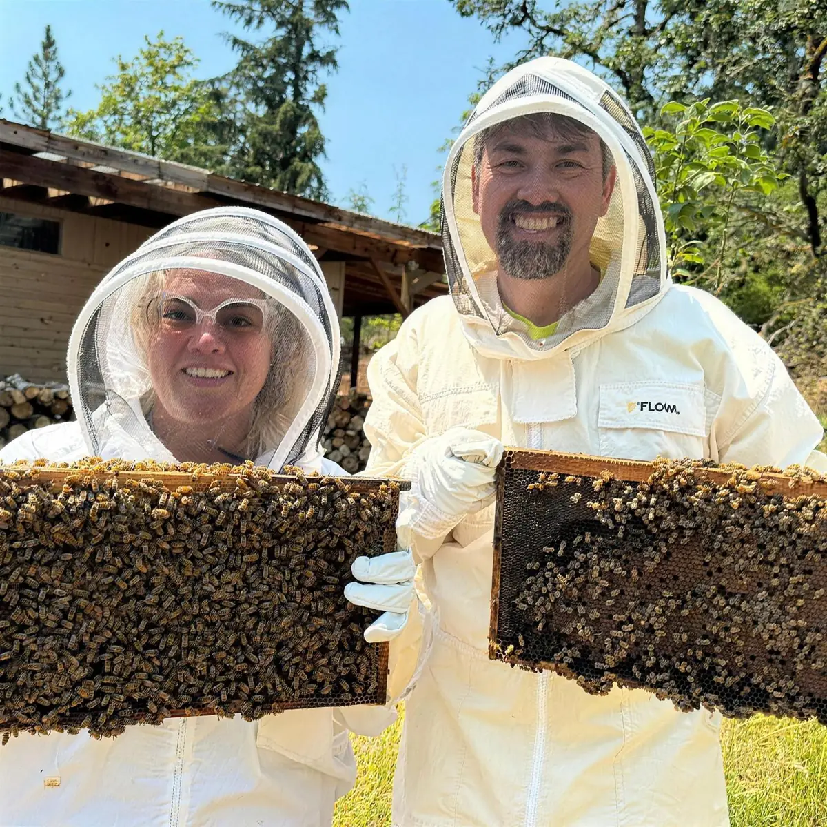 Kathryn and Geoff in bee suits holding frames